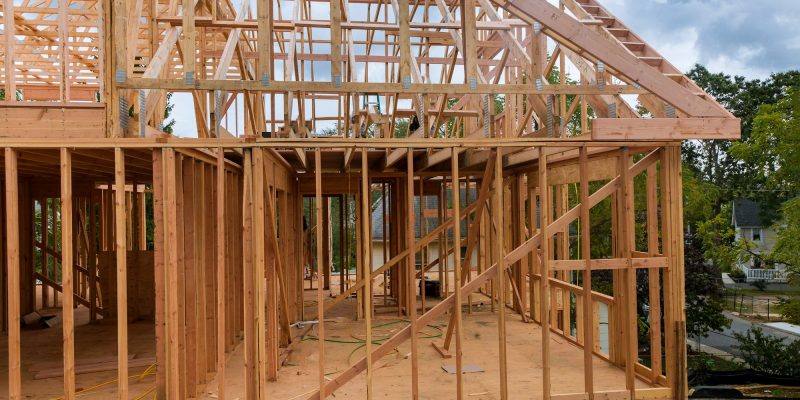 Condominium building with under construction wooden house with timber framing