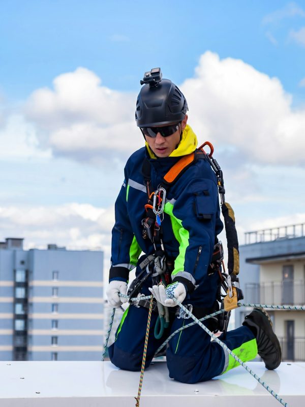 Industrial mountaineering worker in work uniform helmet on roof building during high-rise work